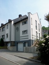 Blick auf Mehrfamilienhaus-Anbau mit Garage von der Strasse aus